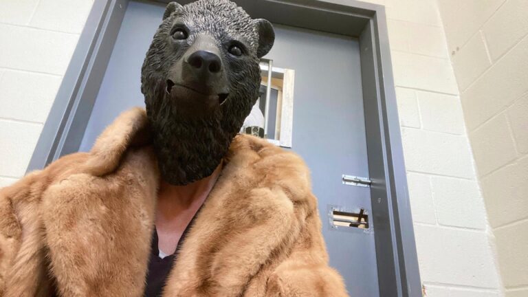 Orphaned cub finds comfort in a teddy bear and costumed caregivers